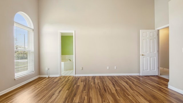 empty room featuring a high ceiling and hardwood / wood-style flooring