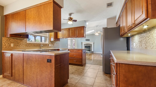 kitchen with light tile patterned floors, kitchen peninsula, stainless steel appliances, decorative backsplash, and ceiling fan