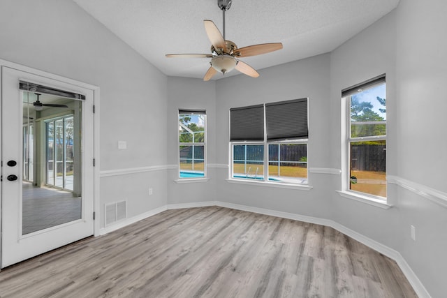 empty room with ceiling fan, light hardwood / wood-style floors, and a textured ceiling