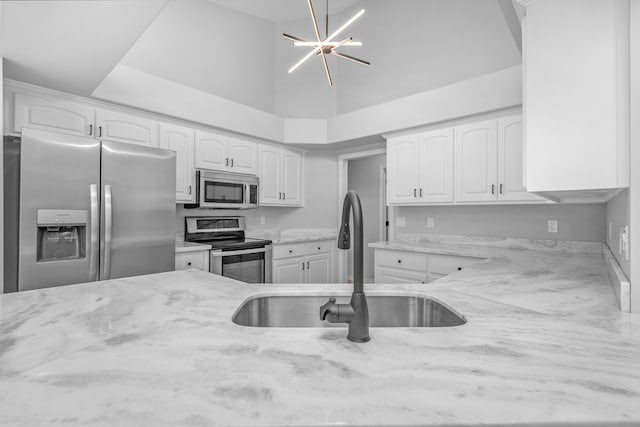 kitchen with sink, light stone countertops, appliances with stainless steel finishes, and white cabinetry