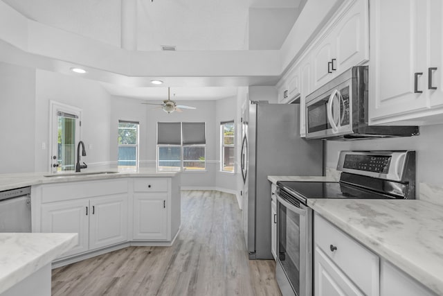 kitchen with light wood-type flooring, sink, appliances with stainless steel finishes, and white cabinetry