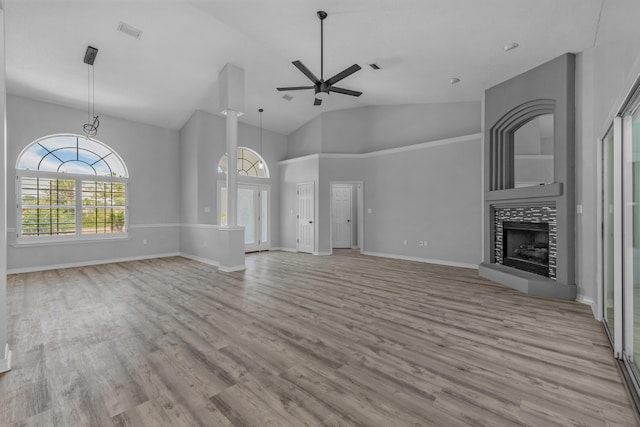 unfurnished living room featuring light wood-type flooring, high vaulted ceiling, ceiling fan, and a tile fireplace