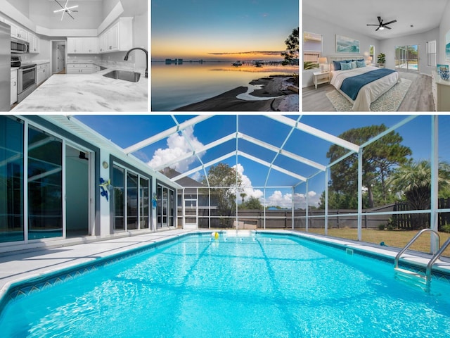 view of swimming pool with ceiling fan, glass enclosure, and sink