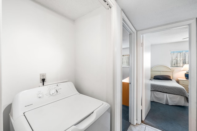 laundry area featuring light carpet, a textured ceiling, and washer / clothes dryer