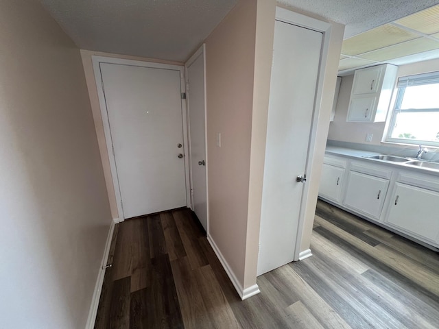 corridor with a sink, baseboards, and wood finished floors