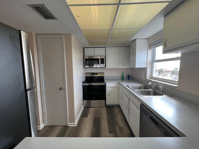 kitchen with visible vents, white cabinets, dark wood-style floors, appliances with stainless steel finishes, and a sink