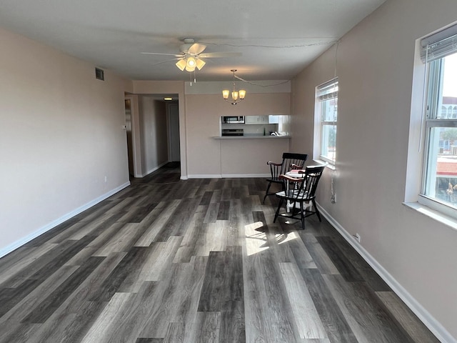 dining area with baseboards, visible vents, wood finished floors, and ceiling fan with notable chandelier