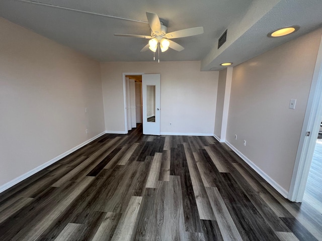 spare room featuring a ceiling fan, dark wood-style flooring, visible vents, and baseboards