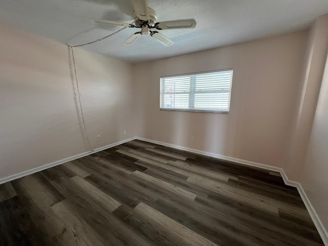 empty room with a ceiling fan, baseboards, and dark wood-type flooring