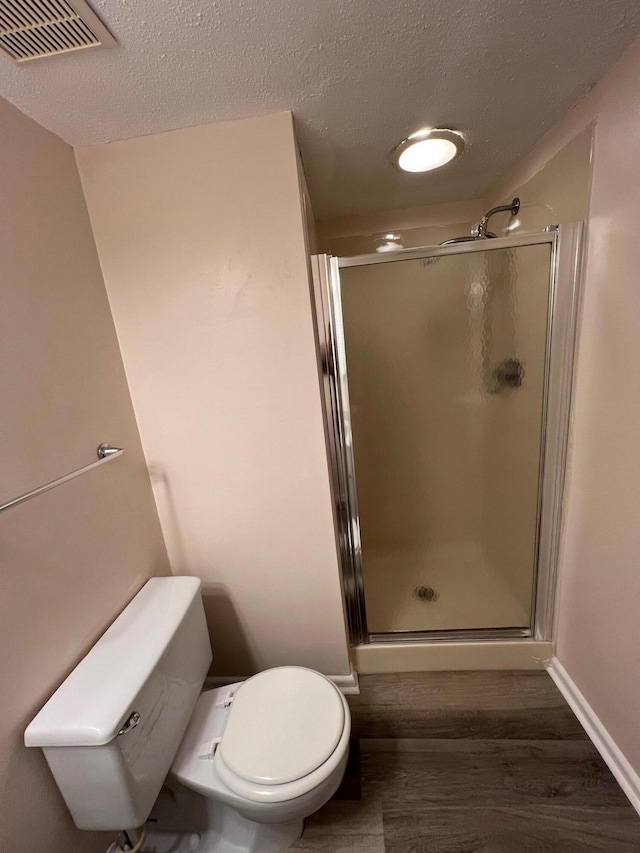 full bath featuring a stall shower, visible vents, toilet, and wood finished floors