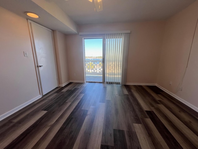 empty room featuring baseboards and dark wood-type flooring