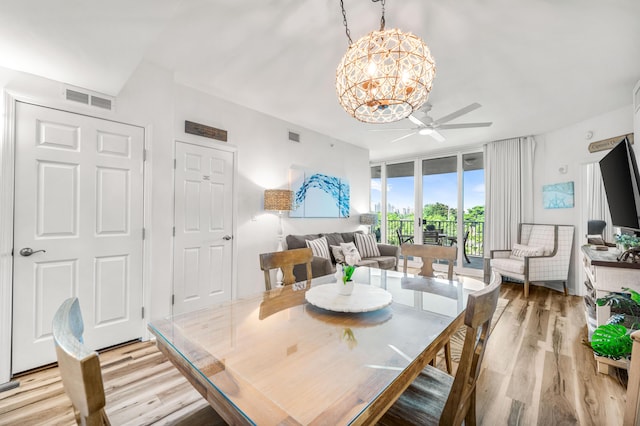 dining space featuring light wood-type flooring, floor to ceiling windows, visible vents, and ceiling fan with notable chandelier