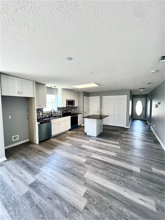 kitchen with white cabinetry, dark hardwood / wood-style flooring, stainless steel appliances, and a textured ceiling