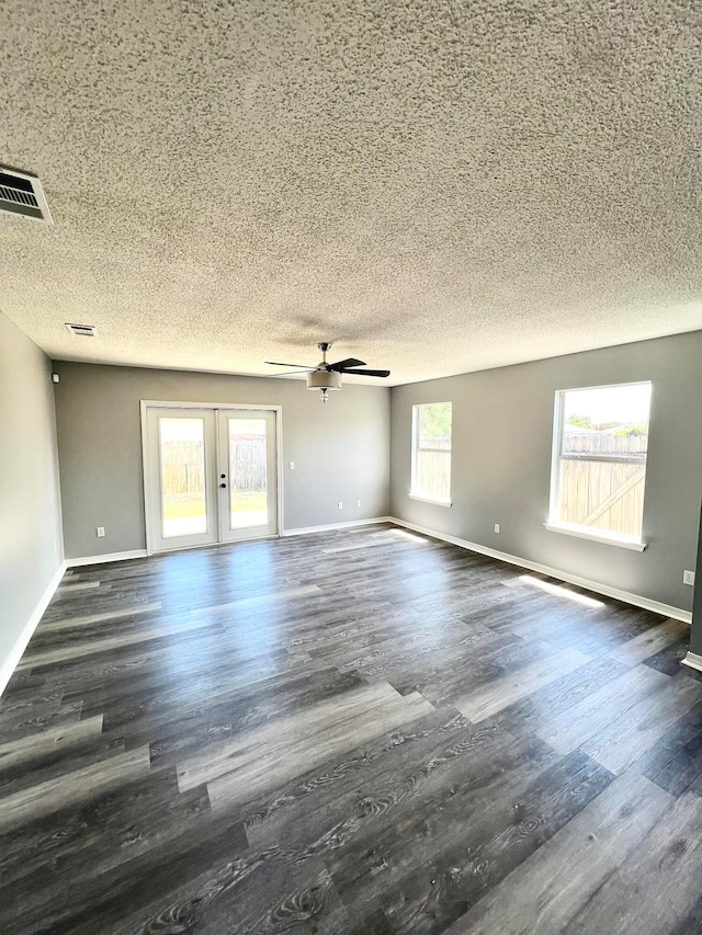 unfurnished living room featuring a wealth of natural light, ceiling fan, and dark hardwood / wood-style floors