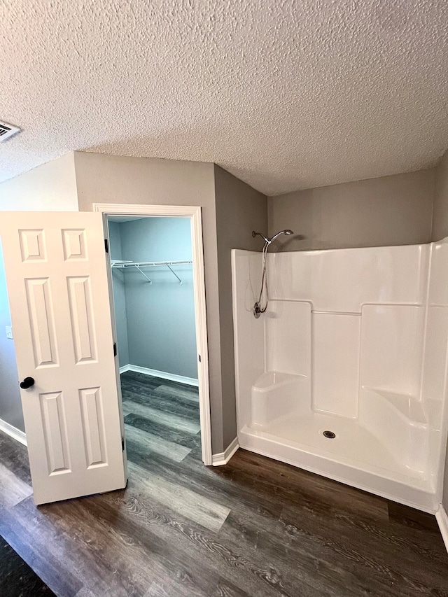 bathroom featuring a textured ceiling, a shower, and hardwood / wood-style floors