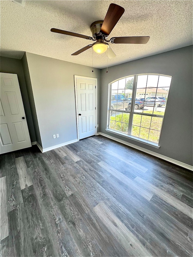 unfurnished bedroom with ceiling fan, dark hardwood / wood-style floors, and a textured ceiling