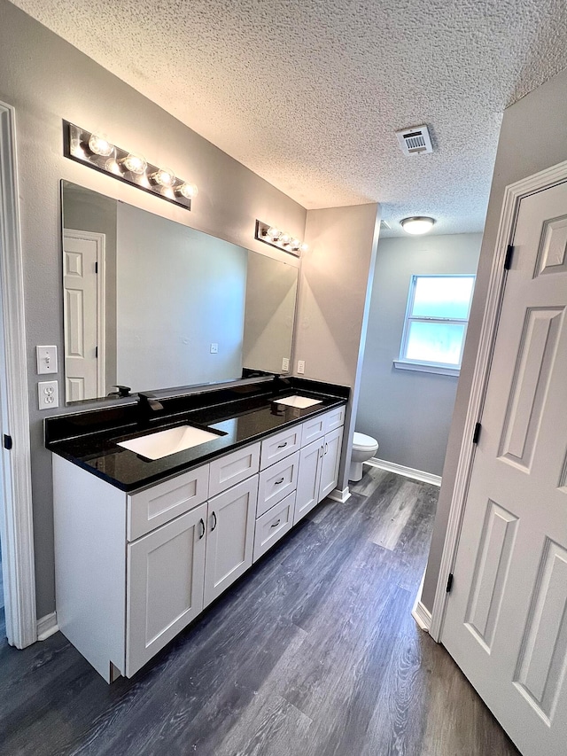 bathroom featuring vanity, toilet, hardwood / wood-style flooring, and a textured ceiling