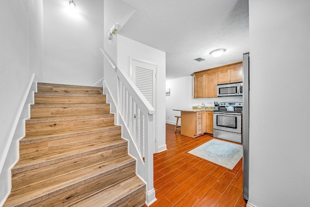 stairs featuring a textured ceiling and hardwood / wood-style flooring