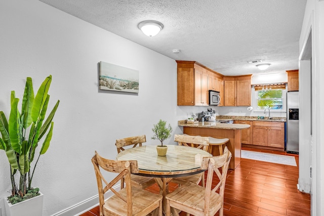 dining area featuring a textured ceiling, sink, and light wood-type flooring