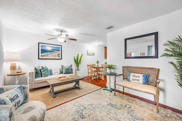 living room featuring a textured ceiling, hardwood / wood-style floors, and ceiling fan