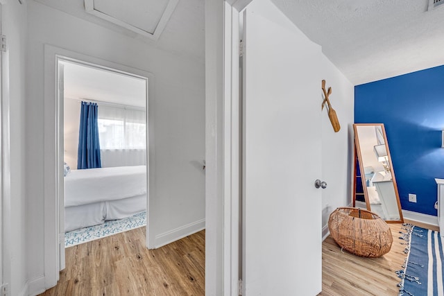 hallway with a textured ceiling and light hardwood / wood-style floors