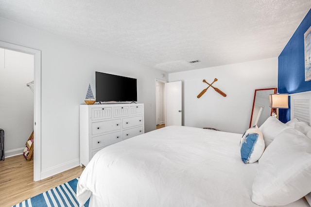 bedroom with a textured ceiling and light hardwood / wood-style flooring