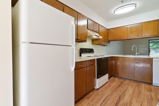 kitchen with white appliances, light hardwood / wood-style flooring, sink, and a textured ceiling