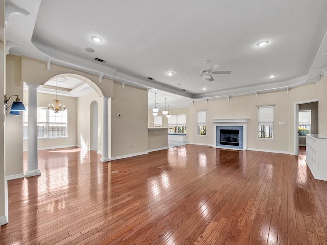 unfurnished living room featuring hardwood / wood-style floors, ceiling fan with notable chandelier, and a healthy amount of sunlight