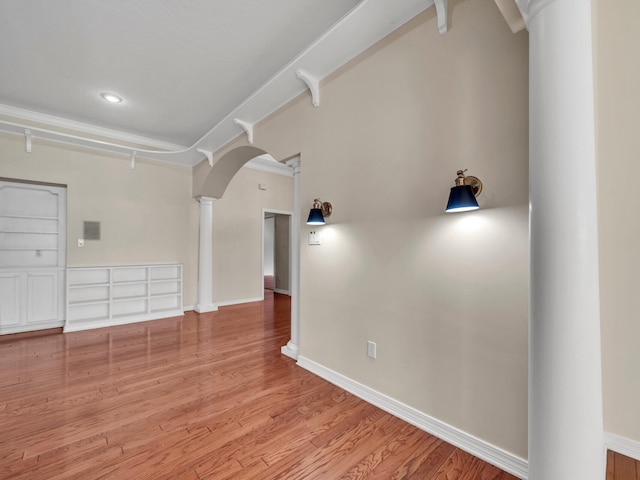 unfurnished room with light wood-type flooring and ornate columns