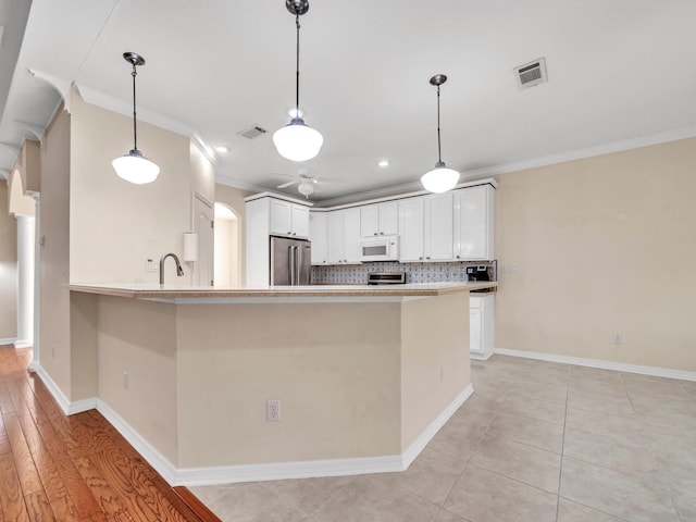 kitchen with kitchen peninsula, appliances with stainless steel finishes, light hardwood / wood-style floors, white cabinets, and ornamental molding