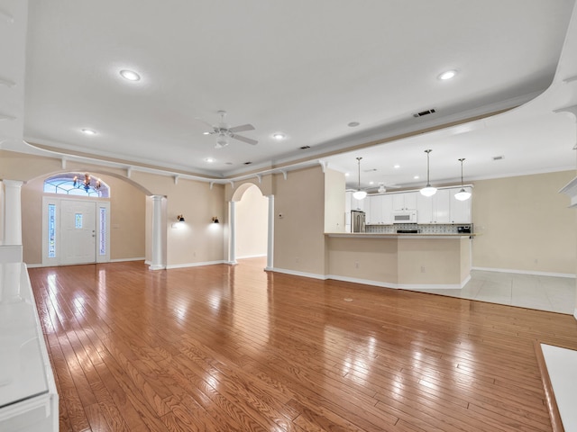 unfurnished living room with ceiling fan, light hardwood / wood-style floors, and ornamental molding