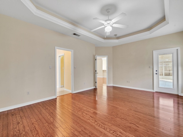 unfurnished room with a tray ceiling, ceiling fan, and light hardwood / wood-style floors