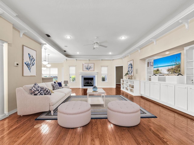 living room with a fireplace, hardwood / wood-style floors, ceiling fan, and crown molding