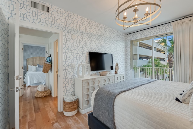 bedroom with access to outside, light hardwood / wood-style flooring, and a chandelier