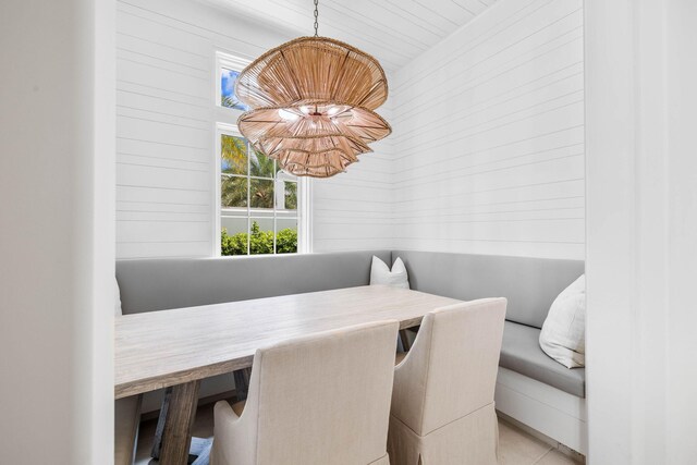 tiled dining area with wooden ceiling and wood walls