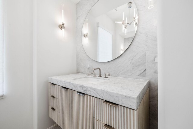 bathroom with vanity, tile walls, and an inviting chandelier