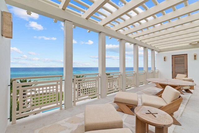 interior space with a water view, a beach view, and a pergola