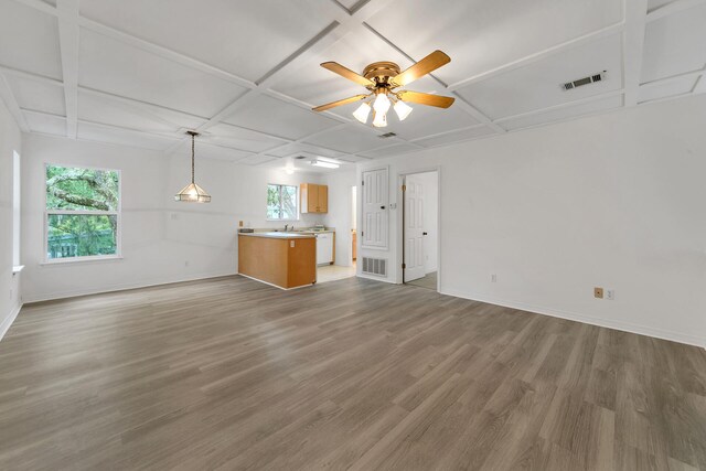 unfurnished living room with a wealth of natural light, ceiling fan, dark hardwood / wood-style floors, and coffered ceiling