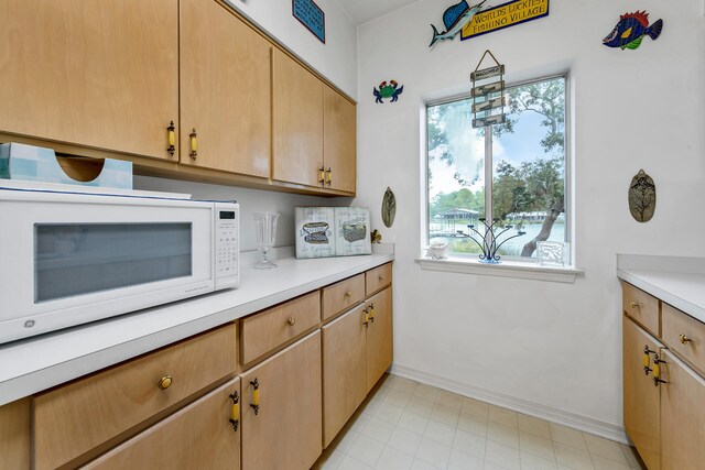 kitchen with light brown cabinetry and hanging light fixtures