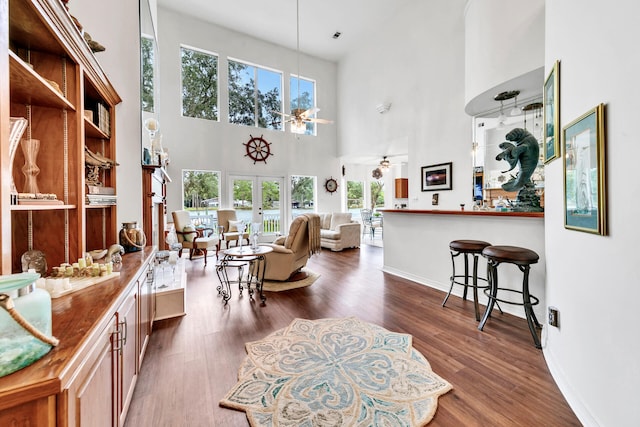 living room with ceiling fan, french doors, dark wood-type flooring, and a high ceiling