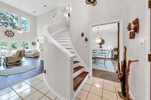 stairway featuring a wealth of natural light, tile patterned flooring, a towering ceiling, and french doors