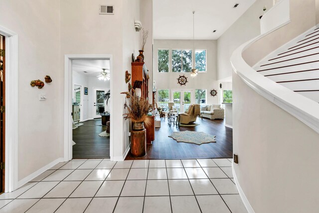 hallway with light tile patterned floors and a towering ceiling