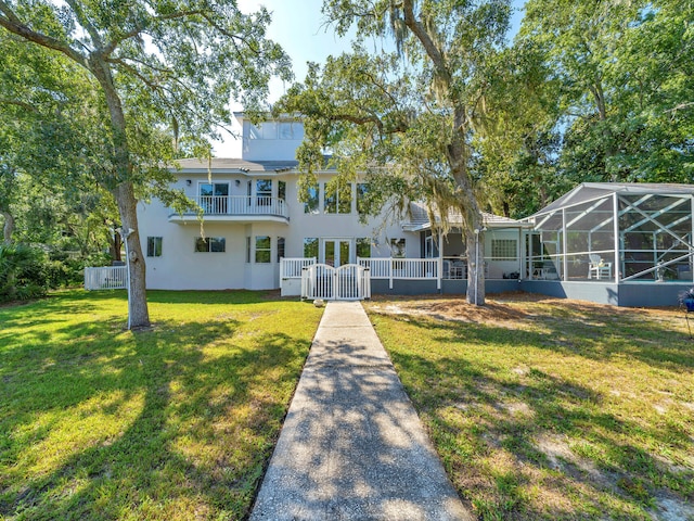 664 Woodland Bayou Dr, Santa Rosa Beach, FL 32459 - view of front of property with a gate, a balcony, stucco siding, fence private yard, and a front lawn