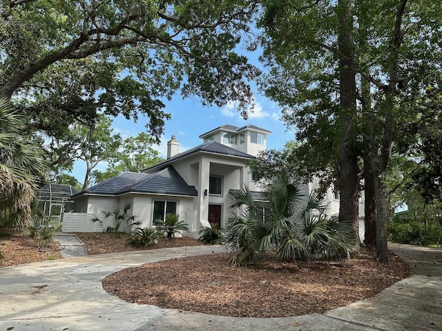 664 Woodland Bayou Dr, Santa Rosa Beach, FL 32459 - view of front of home with stucco siding, a chimney, and curved driveway