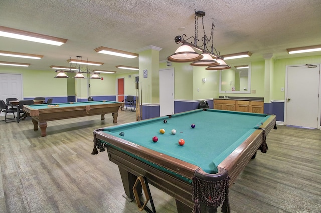playroom featuring billiards table, a textured ceiling, a sink, and light wood-style flooring
