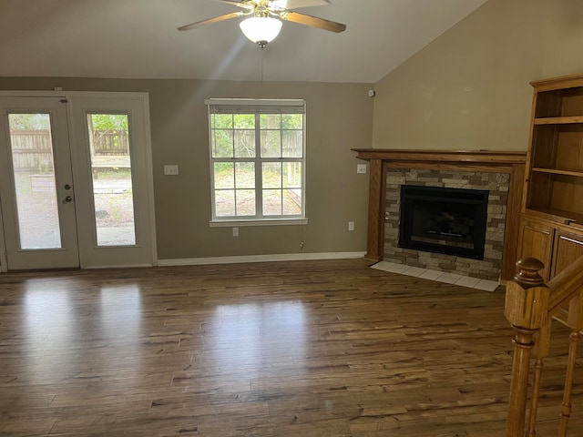 unfurnished living room with vaulted ceiling, a stone fireplace, ceiling fan, and dark hardwood / wood-style floors