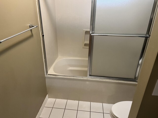 bathroom featuring tile patterned flooring, toilet, and enclosed tub / shower combo