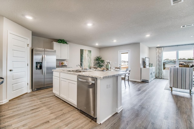 kitchen featuring a center island with sink, a wealth of natural light, visible vents, appliances with stainless steel finishes, and light wood-style floors