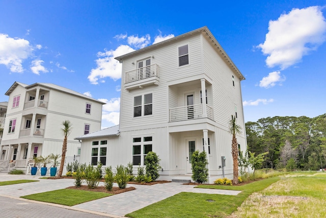 view of front facade featuring board and batten siding, a front yard, and a balcony