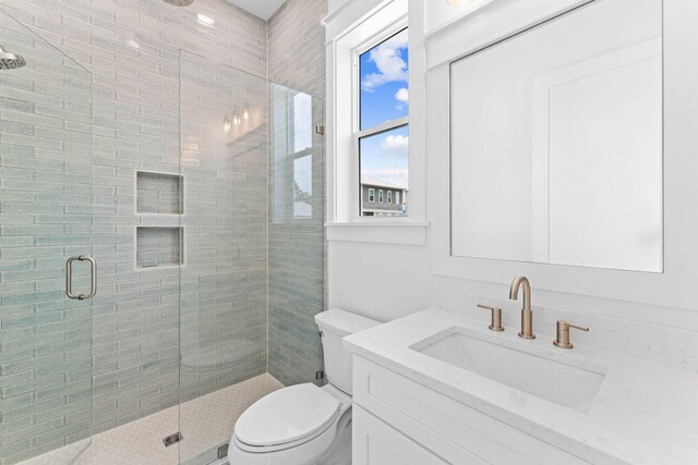 bathroom featuring toilet, a shower with door, and vanity